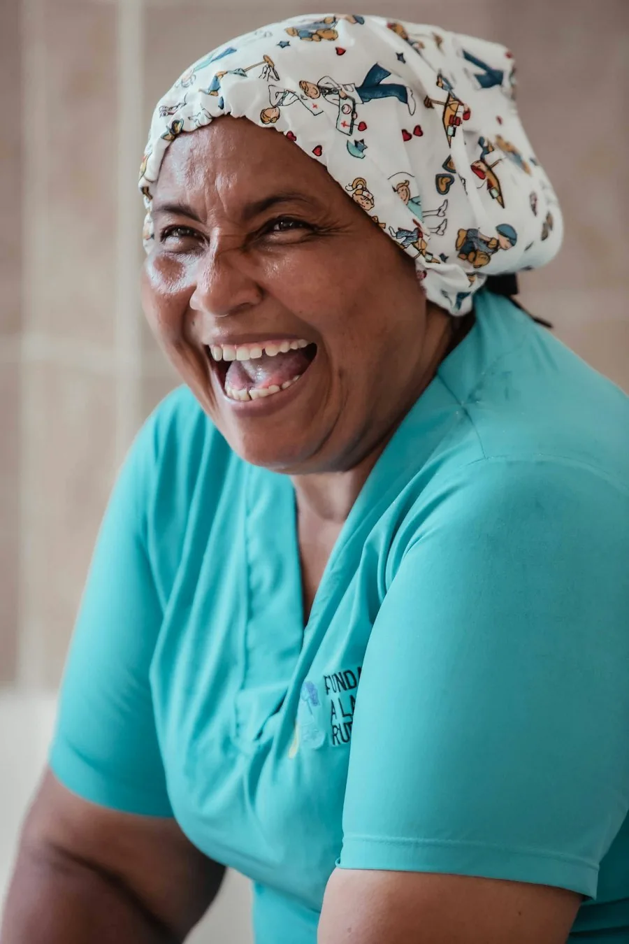 A home care aide in teal scrubs laughing