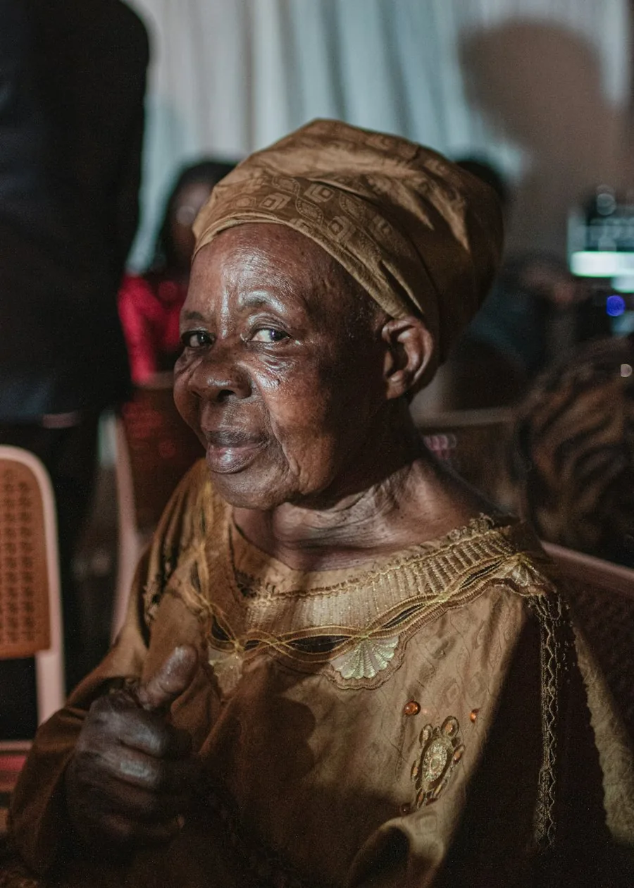 An older woman in a gold headwrap at a community gathering