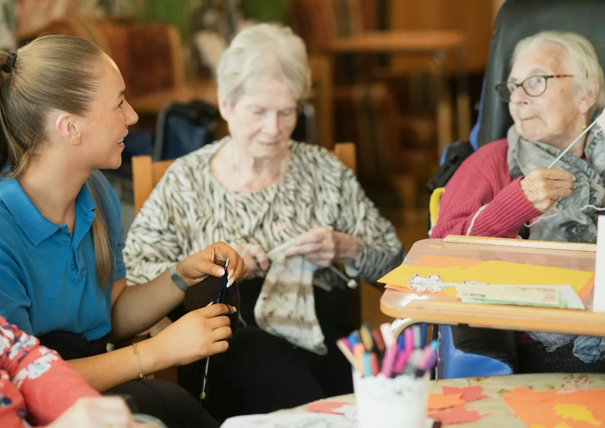 A carer sitting with older women during an afternoon activity